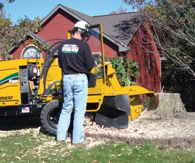Stump grinder working inside a fenced backyard